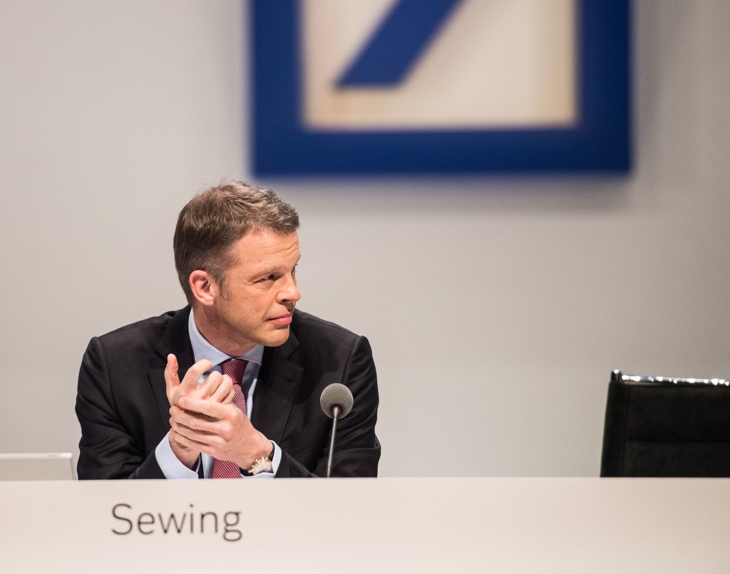 Christian Sewing sits behind a microphone