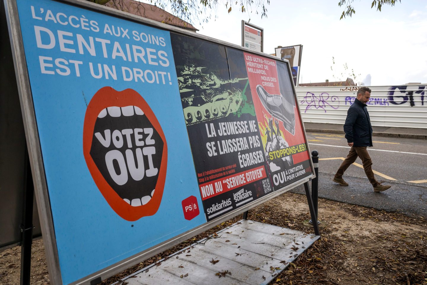 A person walks past referendum posters of political parties and associations in Geneva, Switzerland, on Nov. 26, 2025.