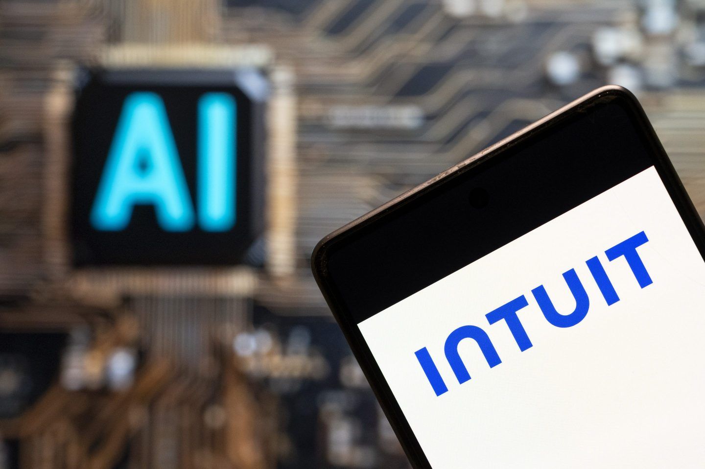 An illustration of the American business software company Intuit logo seen displayed on a smartphone with an Artificial intelligence (AI) chip and symbol in the background.