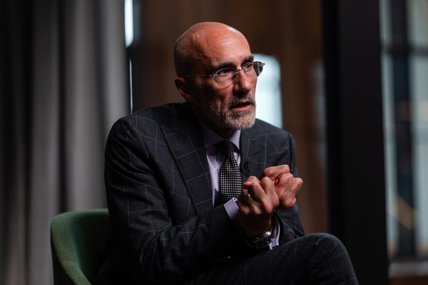 Harvard professor Arthur Brooks clutches his hands while sitting in a chair