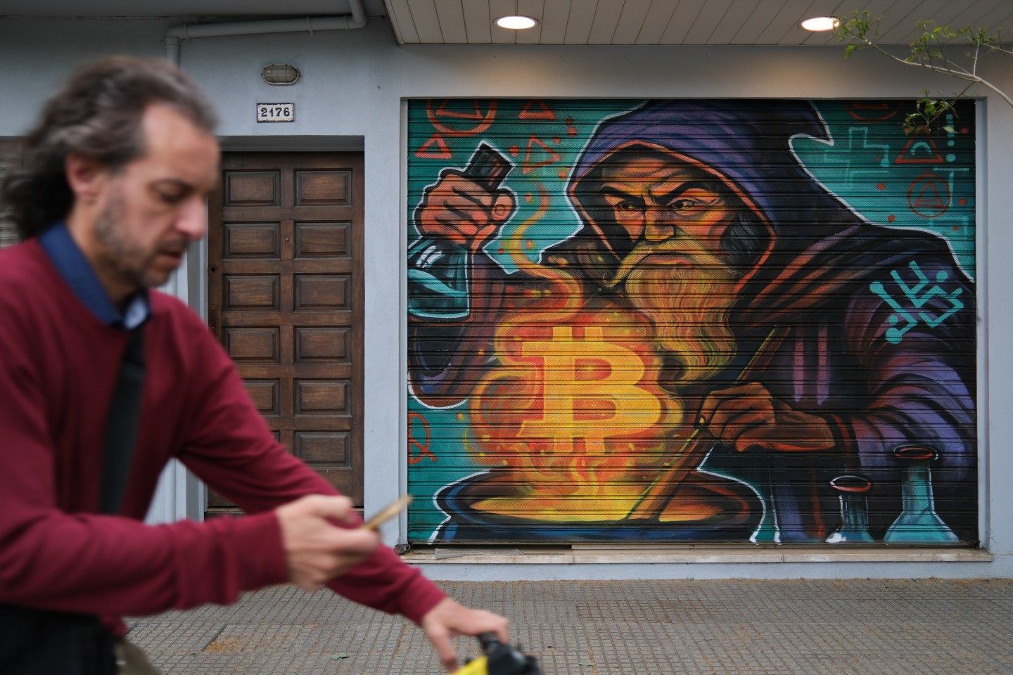Man cycles in front of a Bitcoin mural