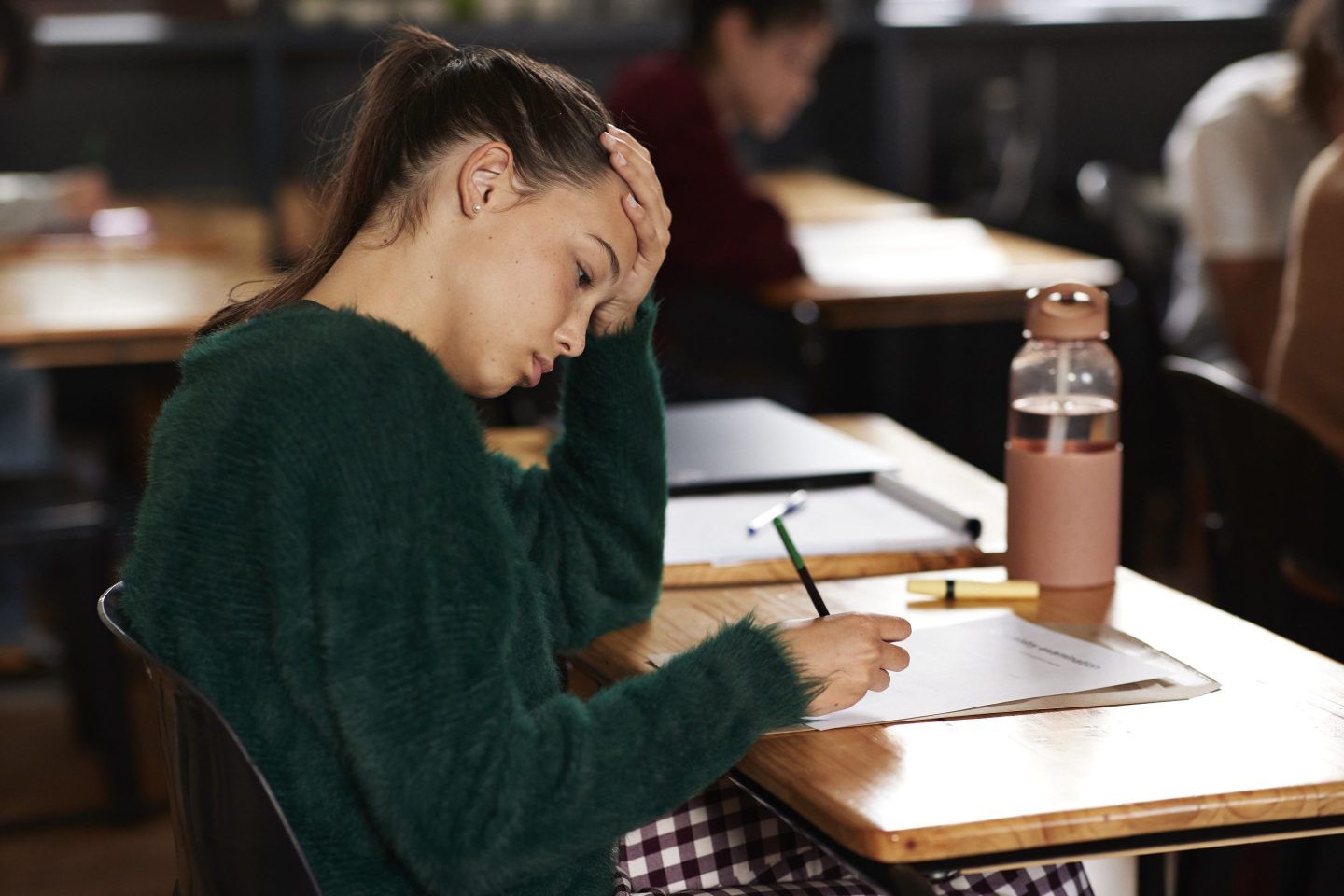 Tensed teenage girl writing on paper