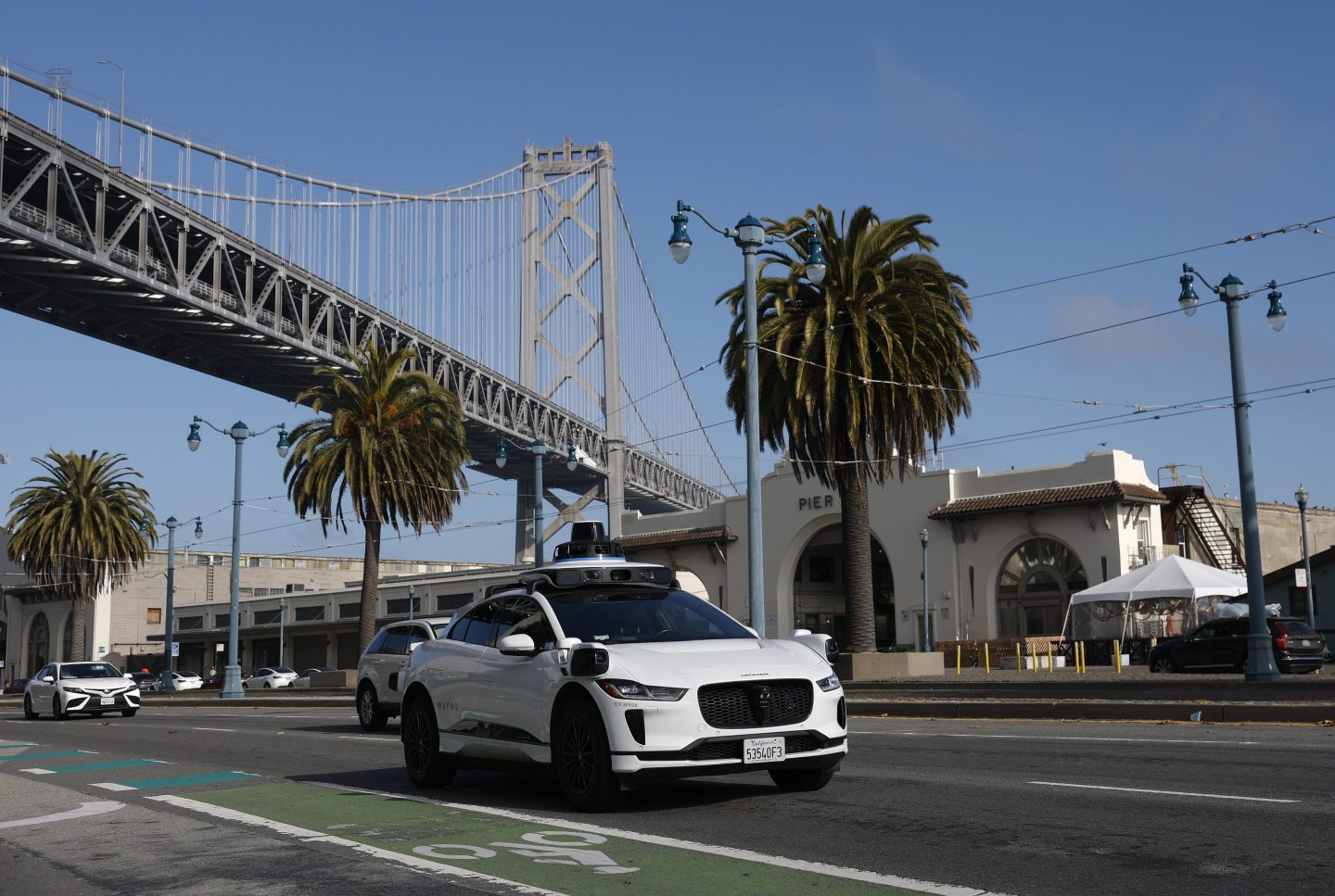 A Waymo robotaxi drives along The Embarcadero on December 08, 2025 in San Francisco, California. Self-driving taxi company Waymo said it is voluntarily recalling software in its autonomous vehicles after Texas officials documented at least 19 incidents this school year in which the cars illegally passed stopped school buses, including while students were getting on or off.