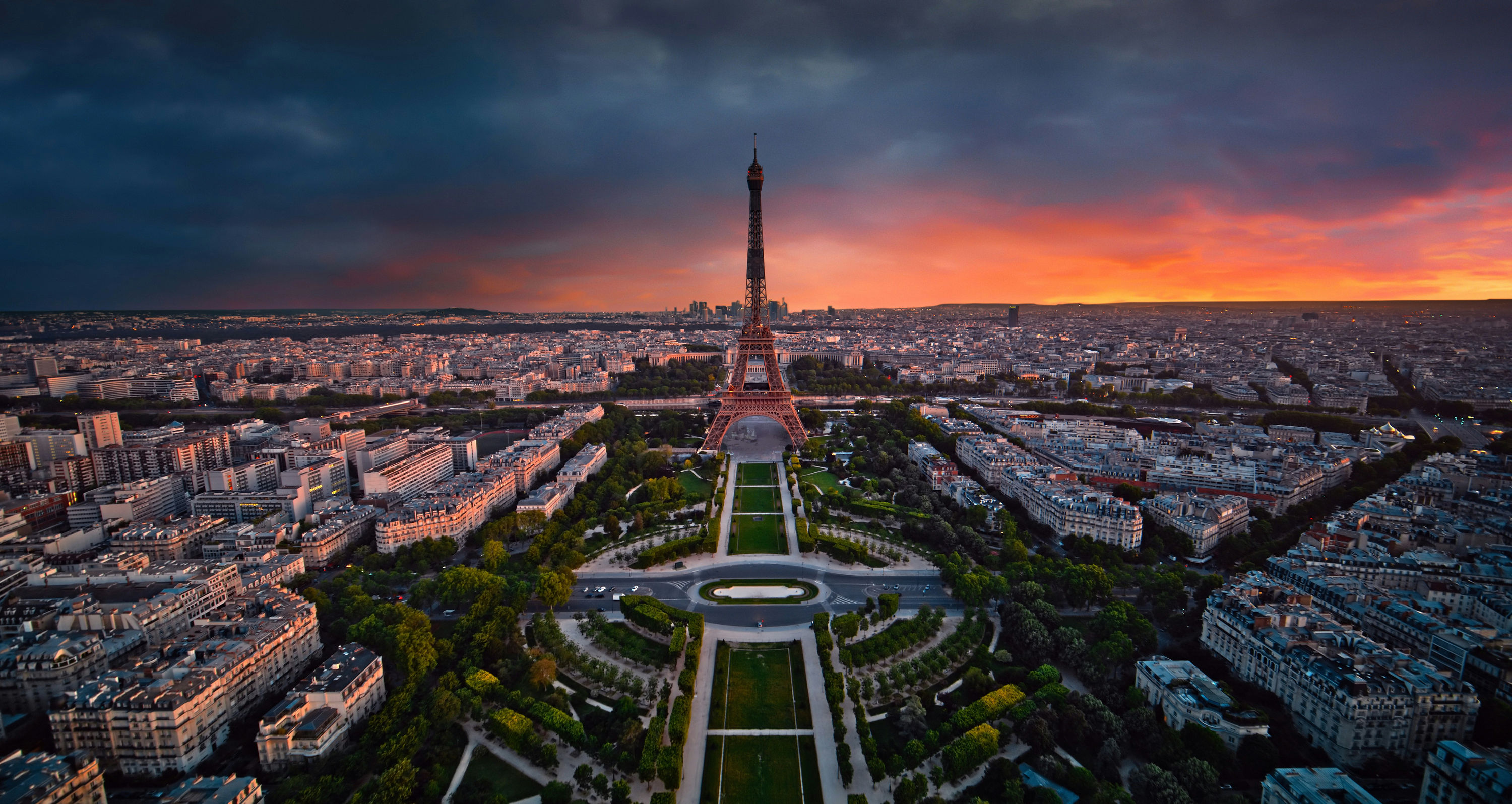 The Eiffel Tower and Champ de Mars during a dramatic orange and purple sunset.