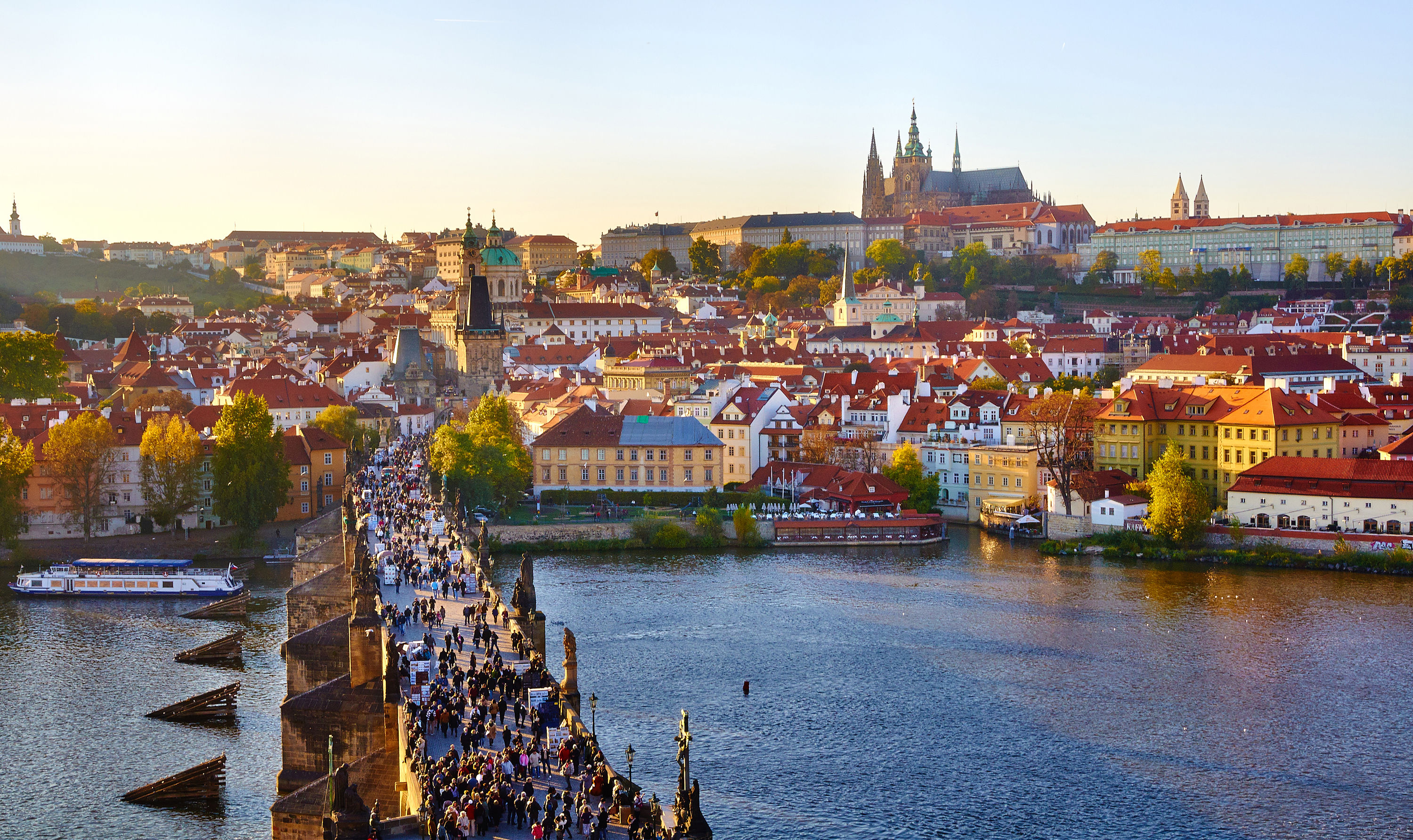 Charles Bridge crossing the Vltava toward Prague Castle at sunset.