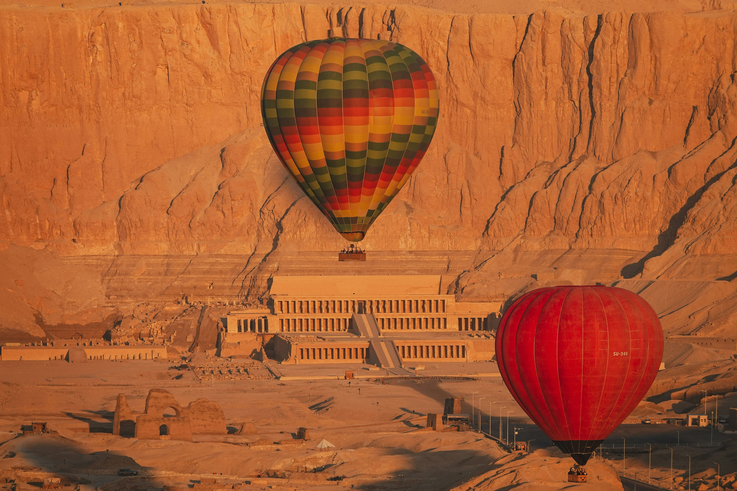 Hot air balloons over the Temple of Hatshepsut and its massive cliff face.