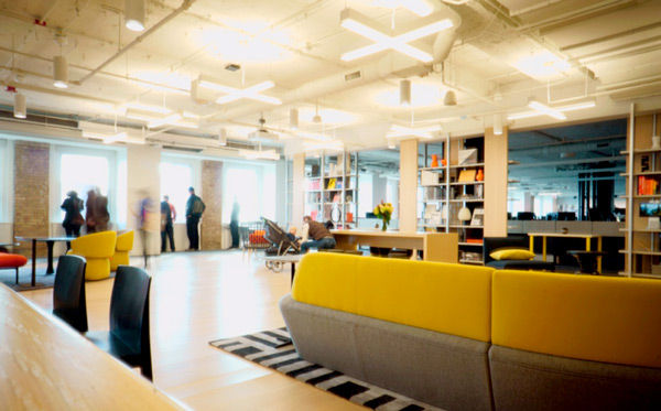 Open airy office with hardwood floors and mustard yellow couches