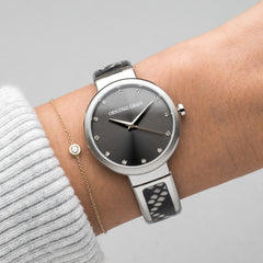 Armreif für Frauen mit Stahl- und Schlangenmuster, 32 mm, am Handgelenk der Frau auf grauem Hintergrund