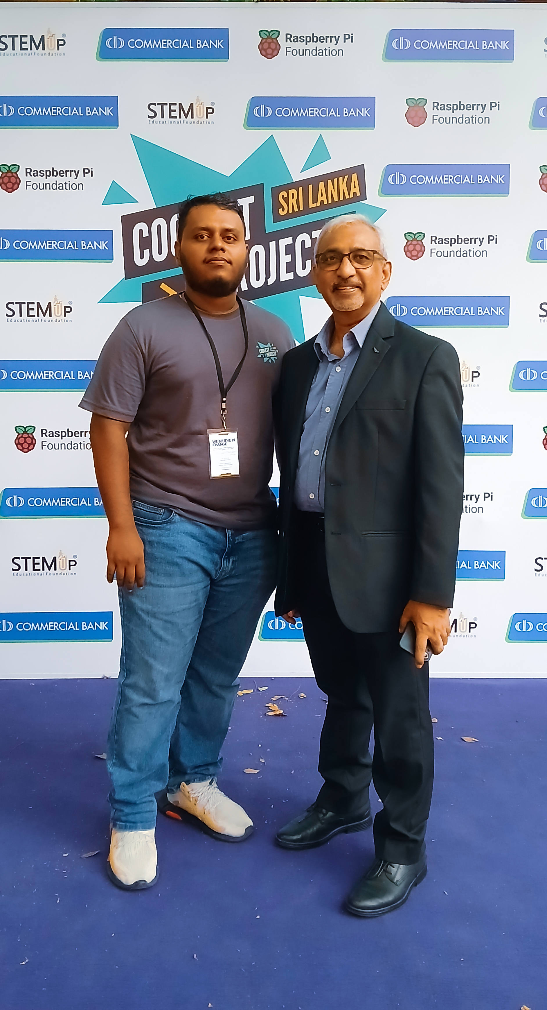 Aweesha Wijesundara with Sujit Christy in front of a sponsor wall at Coolest Projects Sri Lanka 2025
