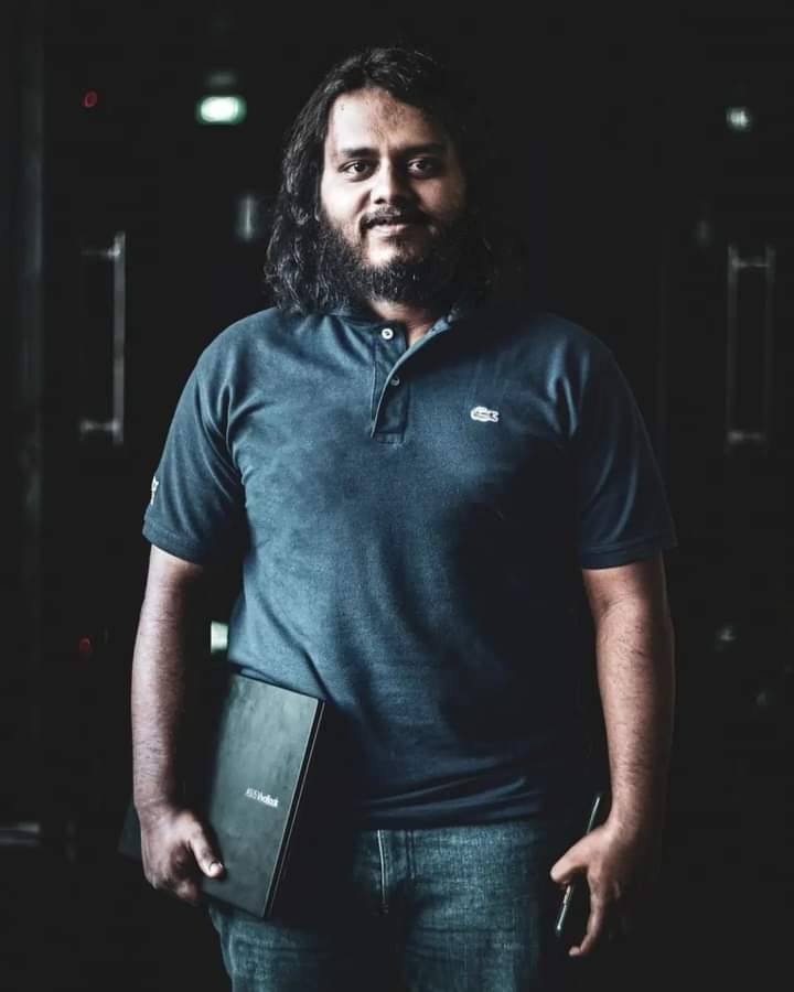 Portrait of Aweesha Wijesundara holding a laptop against a dark background