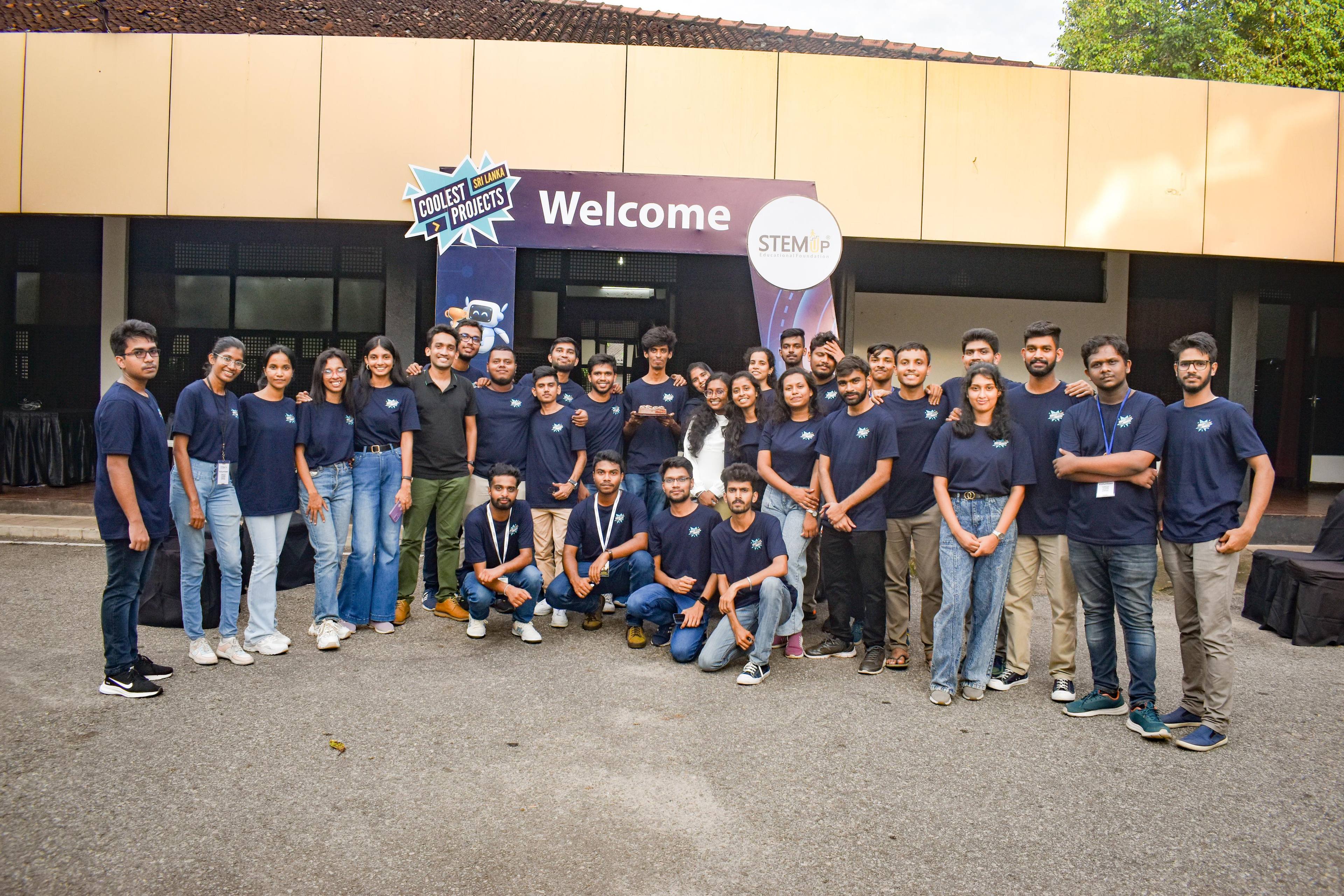 Aweesha Wijesundara with the Coolest Projects Sri Lanka 2024 team in matching navy T-shirts at the event entrance