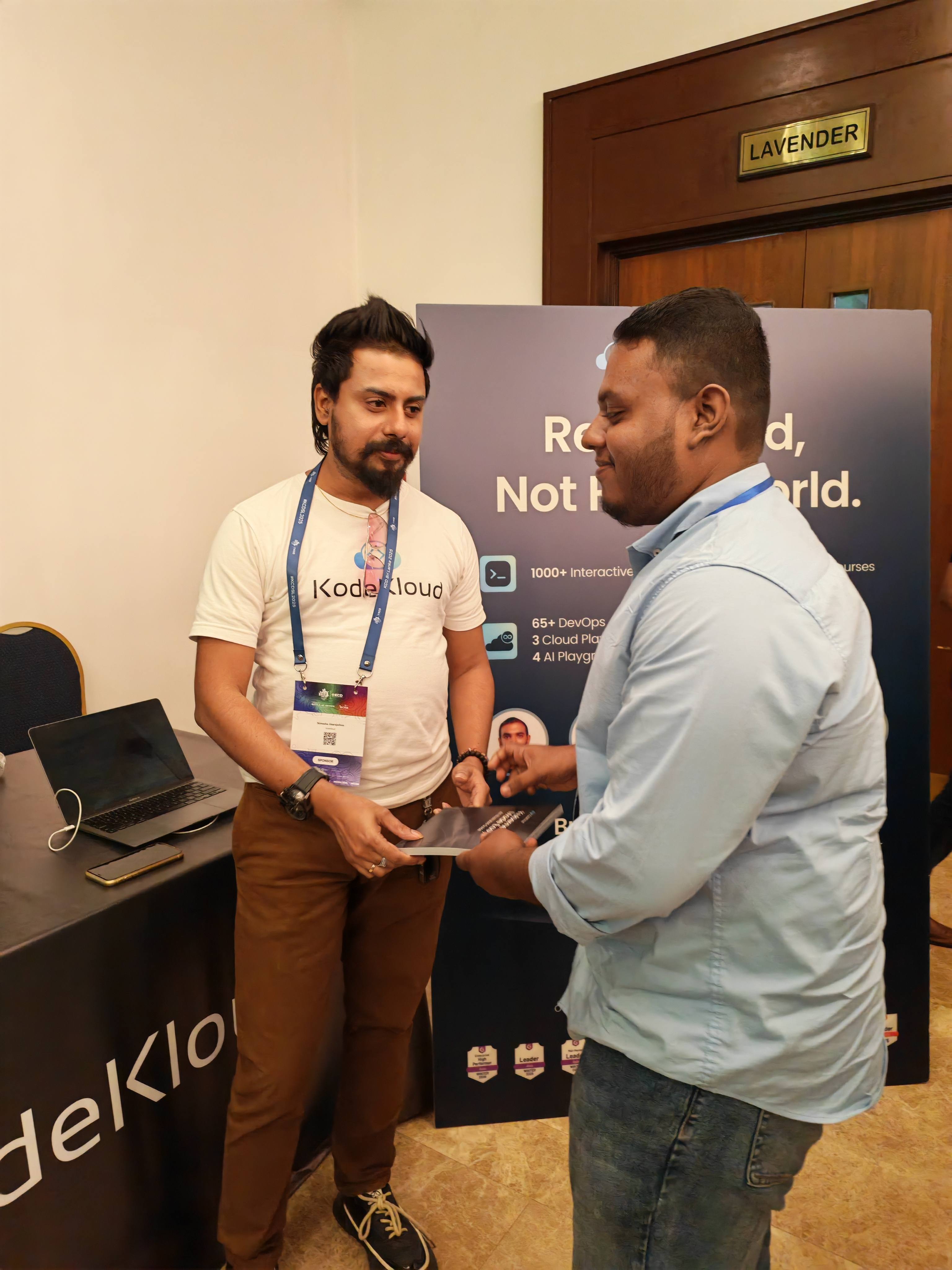 Nimesha Jinarajadasa handing Aweesha Wijesundara a Kubernetes handbook at KCD Sri Lanka 2025