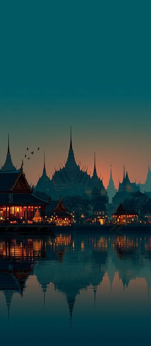 Ornate temple buildings illuminated by lanterns at dusk, with spired silhouettes and reflections in calm river water.