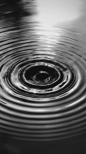Monochrome image of concentric water ripples radiating from a central droplet creating an abstract minimalist pattern.