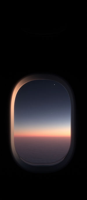 A serene sunrise viewed through an airplane window, showing soft pink and blue hues above a cloudscape at dawn.