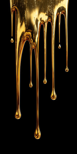 Close-up of glossy gold liquid dripping in long strands against a black background, creating an abstract metallic flow.