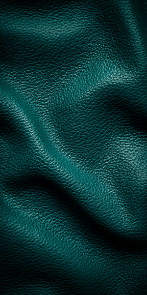 Close-up of teal pebbled leather with glossy highlights, deep folds and textured grain in moody emerald tones.