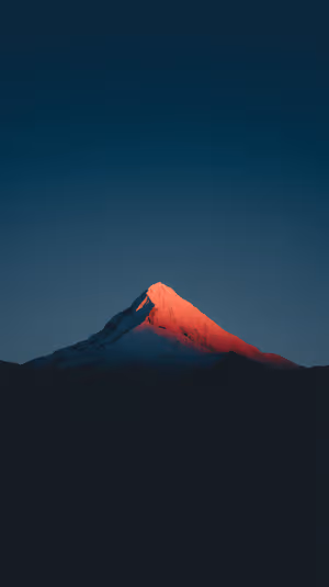 Minimalist mountain peak centered on red alpenglow against a deep blue twilight sky, ultra HD image
