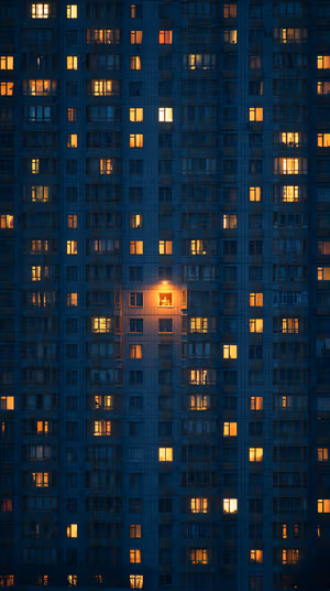 Cinematic urban high rise facade with warm amber windows against a deep blue exterior, ultra HD 8K mobile background.