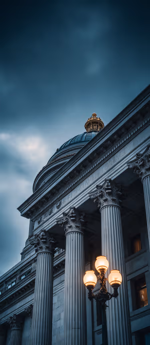 Classical architecture capitol dome and Corinthian columns centered on a moody blue amber dusk background in ultra HD 8K