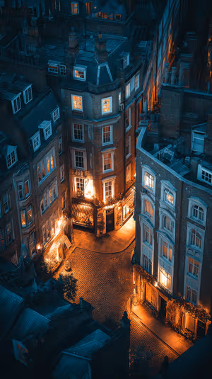 Cinematic aerial view of a cobblestone city corner with warm window glow and teal amber lighting ultra hd image
