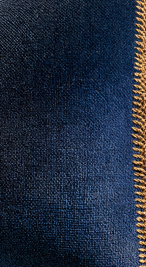 Minimalist denim texture with a gold zipper on a navy blue background in a tactile aesthetic.
