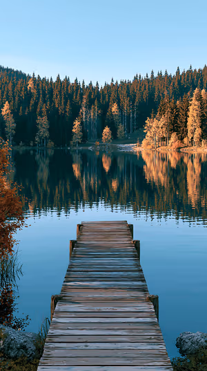 Cinematic wooden dock leading into a blue lake with amber lit forest reflection, ultra HD 8K image