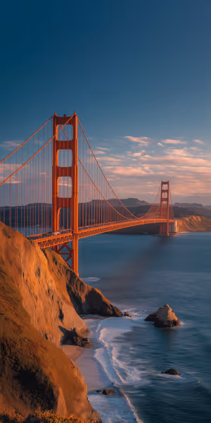 Scenic Golden Gate Bridge centered on warm orange background with coastal cliffs and calm ocean, ultra hd 8K image
