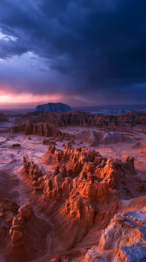 Cinematic hoodoo canyon landscape bathed in red orange sunset with deep blue storm clouds; ultra HD 8K background
