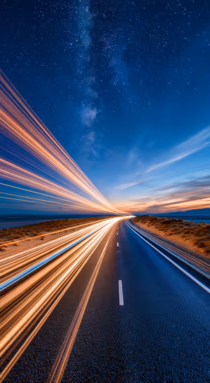Cinematic long exposure highway beneath a deep blue starry sky with orange light trails.