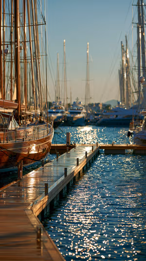 Cinematic sunlit marina with sailboats and wooden dock reflecting teal and gold light ultra hd 8K mobile background.
