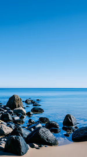 Minimalist rocky shore centered on a clear blue background in a calm coastal aesthetic, ultra HD image.
