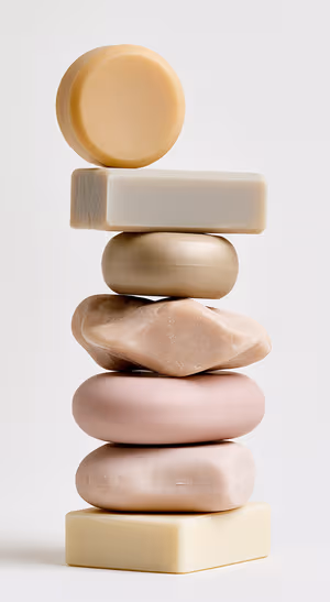 Minimalist stacked soap forms centered on a beige background in minimalist aesthetic.