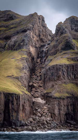 Moody coastal cliff waterfall on a gray green background in a dramatic overcast aesthetic ultra HD 8K image.