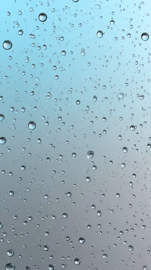 Minimalist close up raindrops on glass centered on a blue gray gradient background in a calming aesthetic.