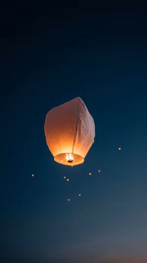 Cinematic sky lantern drifting on a deep blue background with warm orange glow ultra HD 8K image.