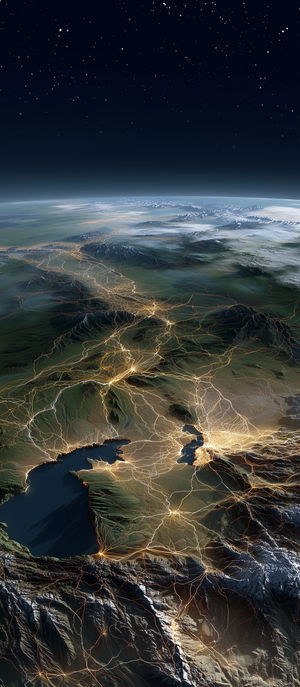 Space view of Earth's glowing highway network and city lights weaving through mountains and lakes.