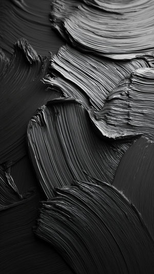Close-up view of abstract black paint brush strokes with textured ridges forming bold monochrome patterns.