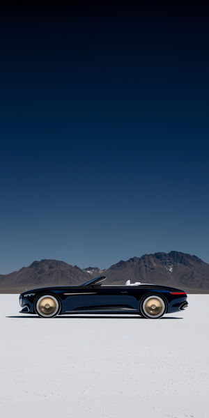 Sleek black convertible car with golden wheels parked on a white salt flat, framed by mountains under a clear blue sky