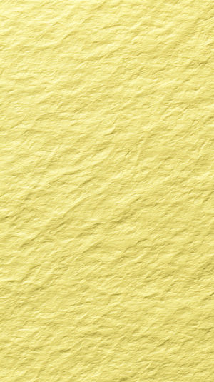 Close-up view of vibrant yellow crumpled paper texture showing subtle creases, uneven surface, and soft shadows