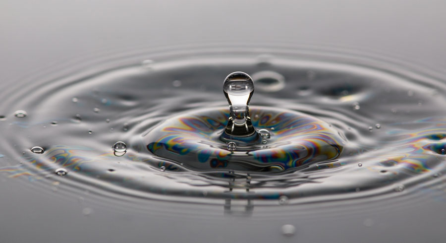 close-up of oil droplets creating rainbow pattern on water surface