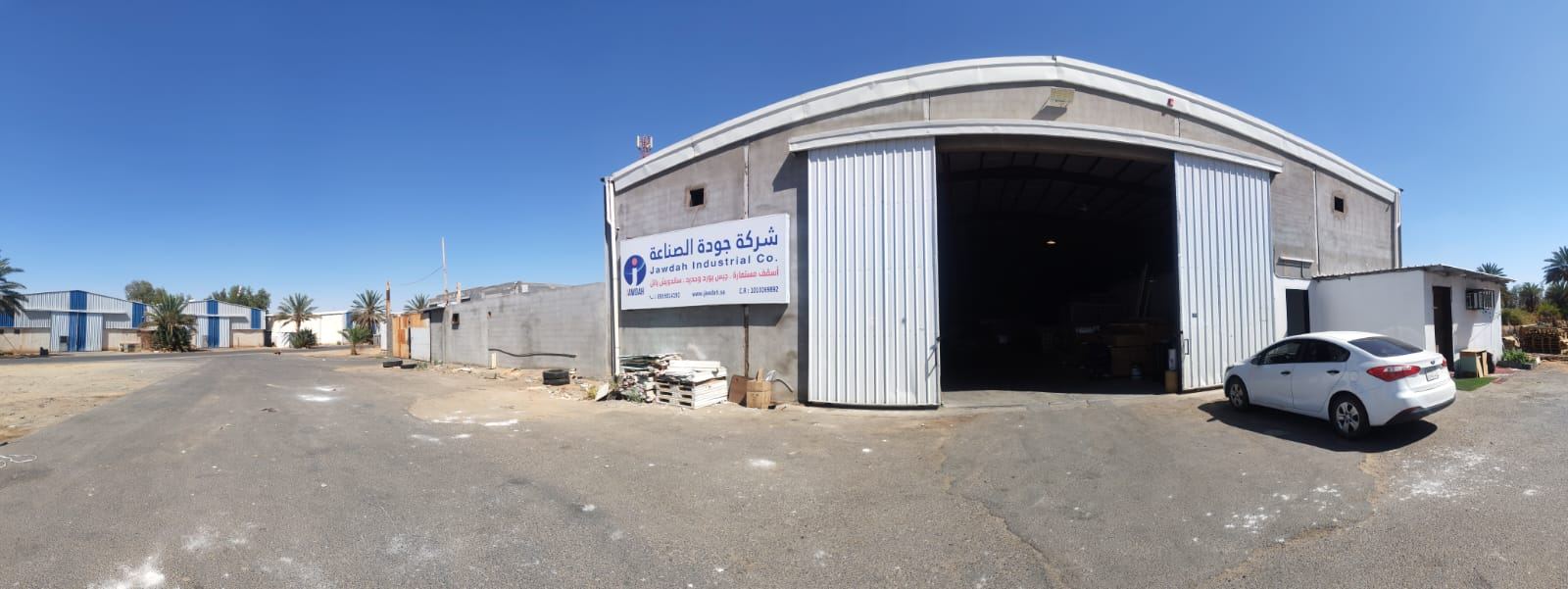 فرع شركة جودة الصناعة في تبوك — الواجهة الخارجية للمستودع ولوحة الشركة
