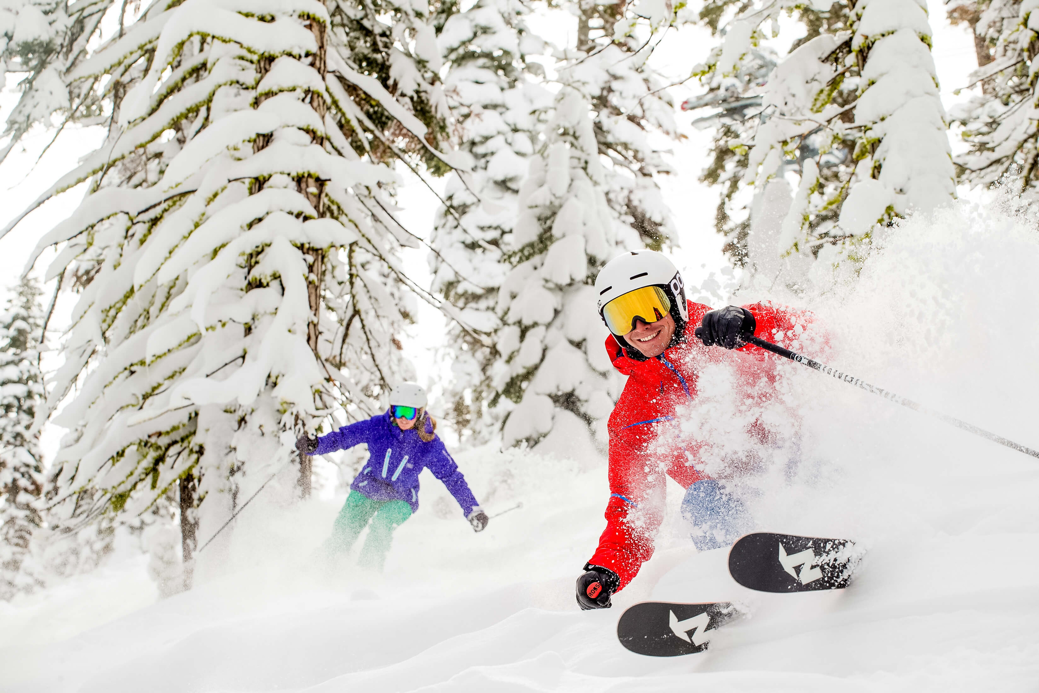 Man and women skiing through the trees