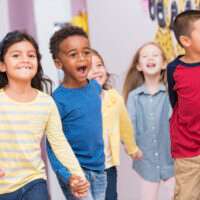 Happy multiracial school children walking thru hallway