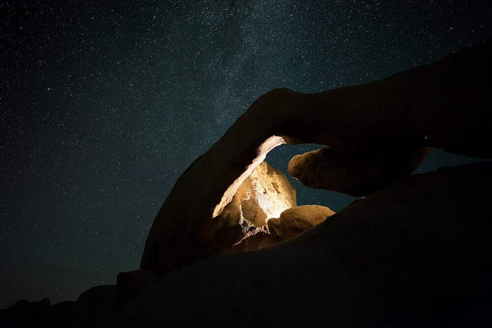 Lit up rock with stars in the background