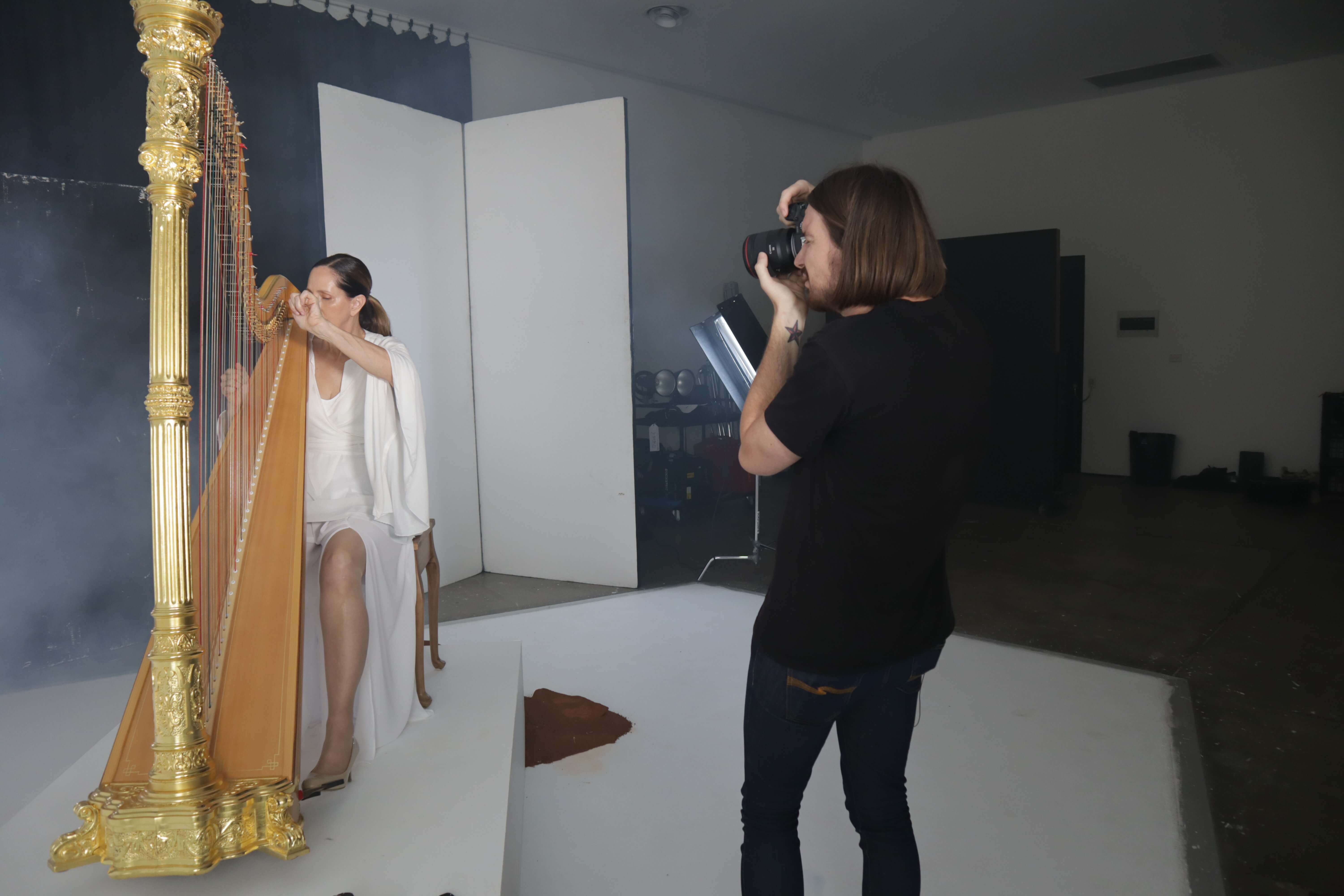 female photographer taking a photo of a woman playing a harp