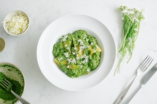 Flat lay of pasta in green sauce in a white bowl on a white marble tabletop, shot with the Panasonic G100 Mirrorless Camera