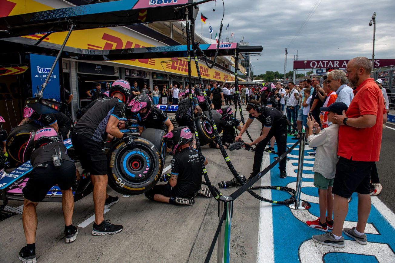 F1 fans watch the Alpine pit crew work during a paddock tour