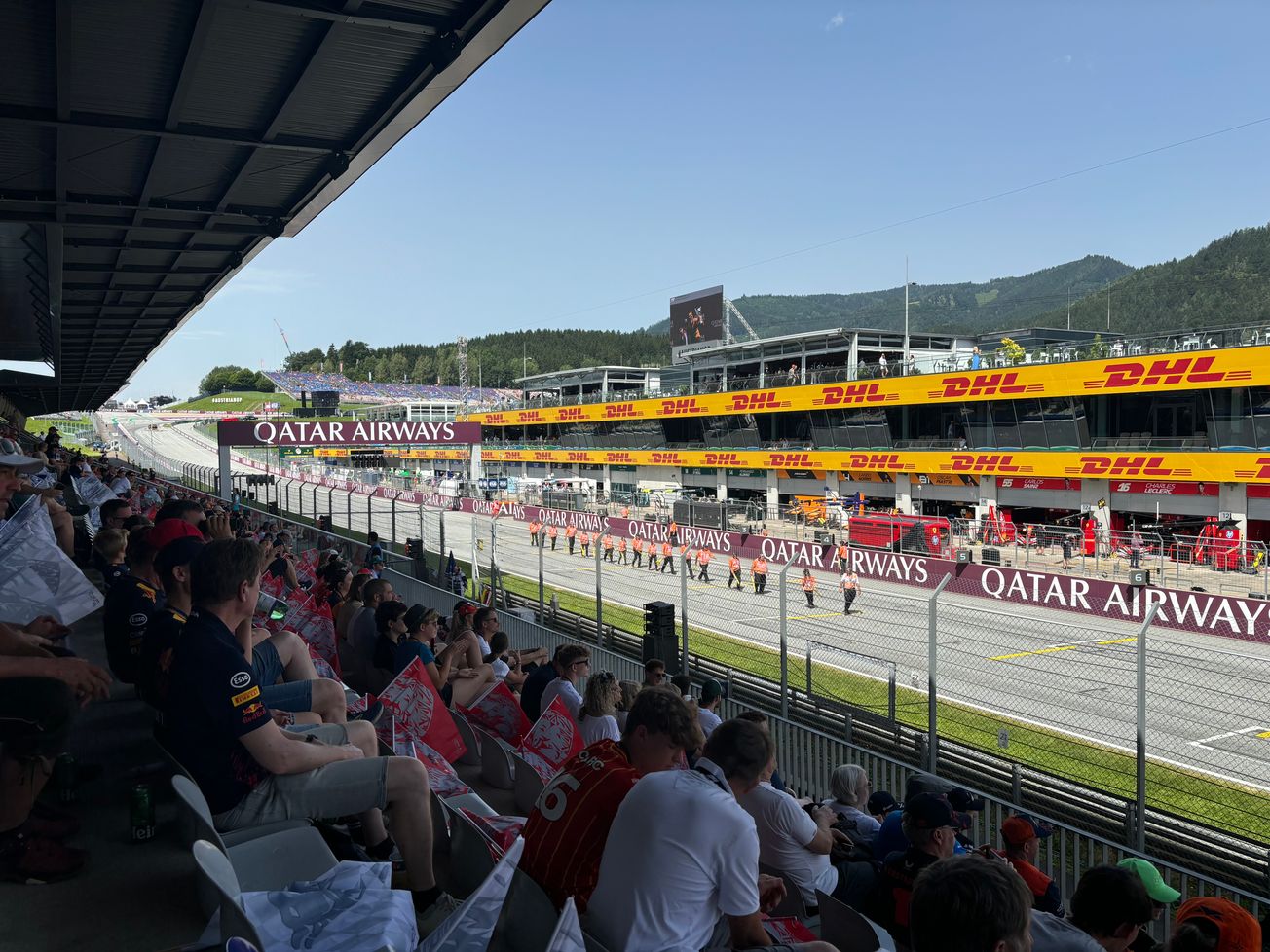 Fans on the Main Grandstand at the Austrian GP while stewards are inspecting the grid