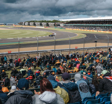 An F1 car in the Chapel-corner while fans are watching from the grandstand